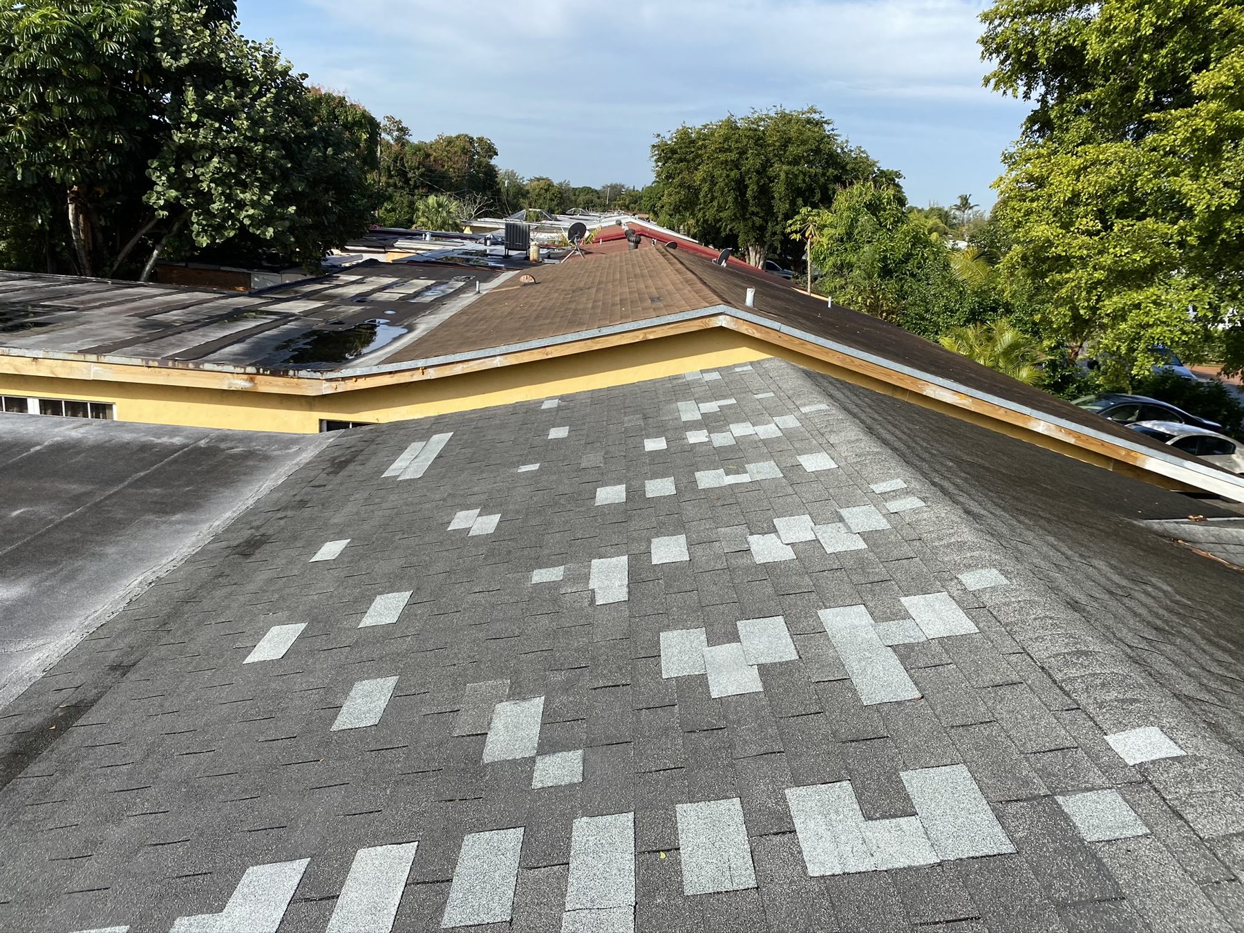 Multi-unit association roofs with wind damage documented from above.